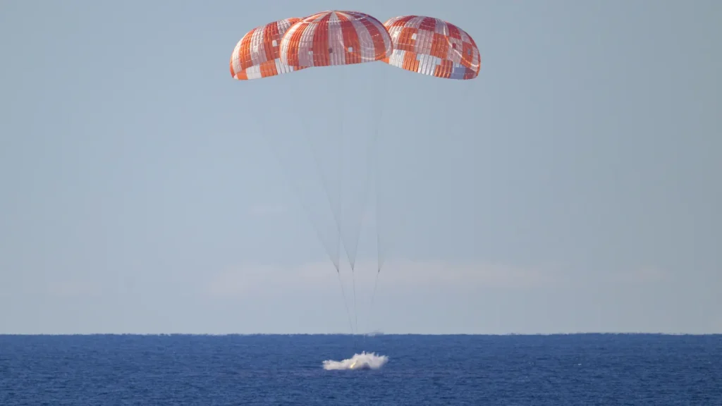 Cápsula Orión amerizando en el océano Pacífico junto al buque de recuperación